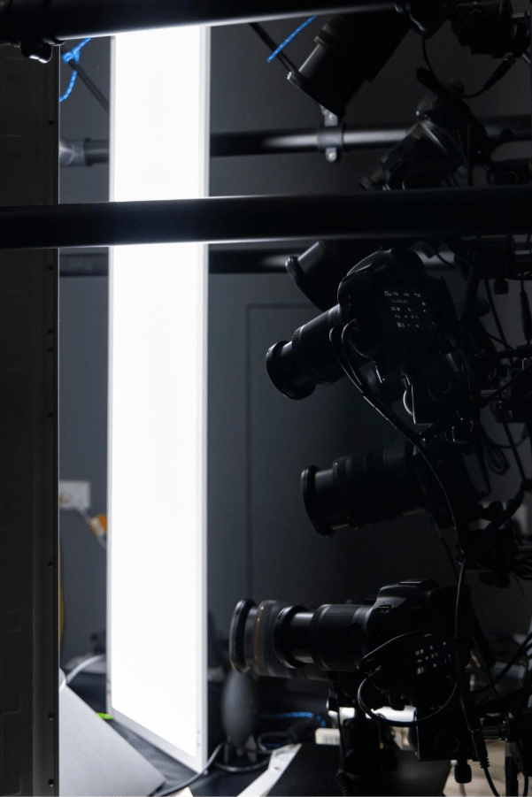 A photography setup featuring multiple cameras positioned beside a bright, vertical light source.